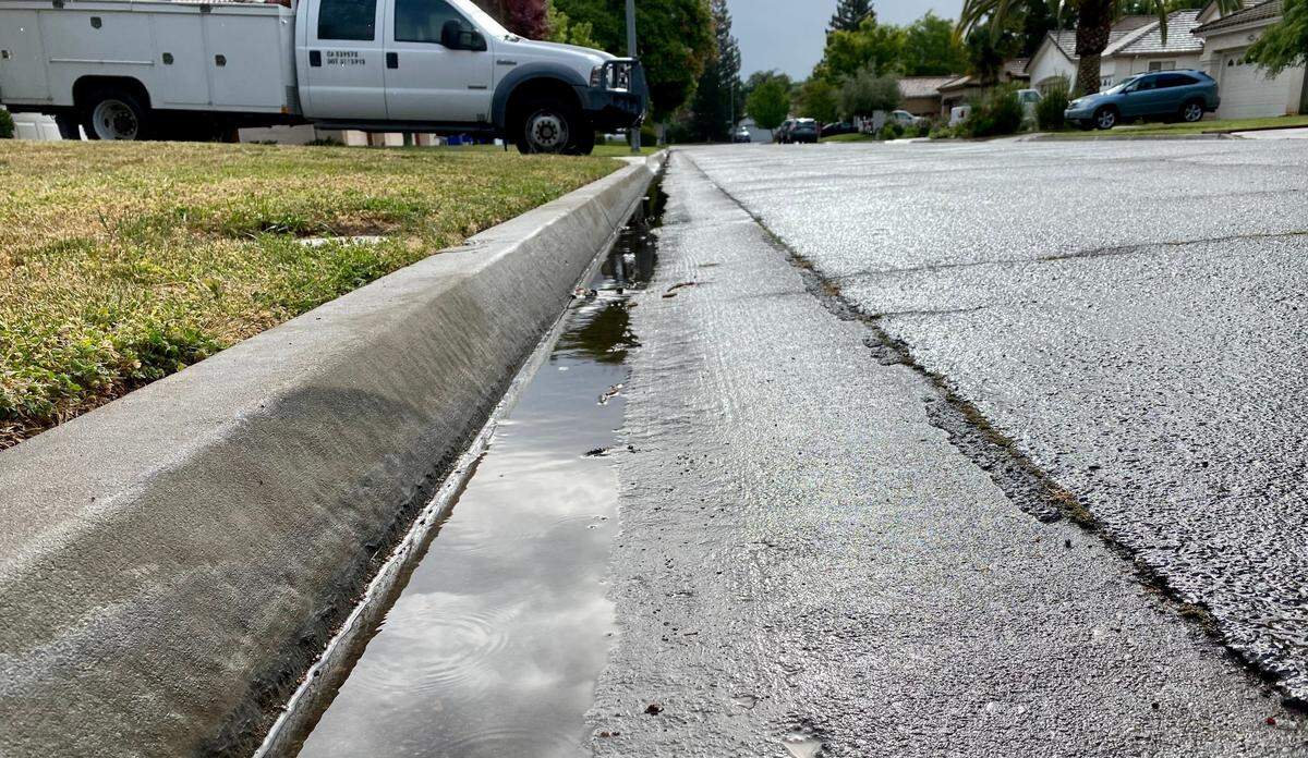 Fresno residents woke to cloudy skies and wet roads on Saturday, April 16, 2022, as a storm dropped trace amounts of rainfall on the central San Joaquin Valley. Enough rain fell to send a trickle of runoff through the gutter on this residential street in northwest Fresno.