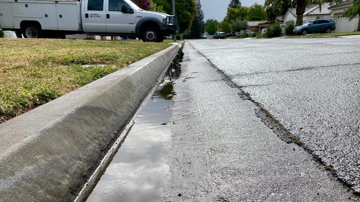 Fresno residents woke to cloudy skies and wet roads on Saturday, April 16, 2022, as a storm dropped trace amounts of rainfall on the central San Joaquin Valley. Enough rain fell to send a trickle of runoff through the gutter on this residential street in northwest Fresno.