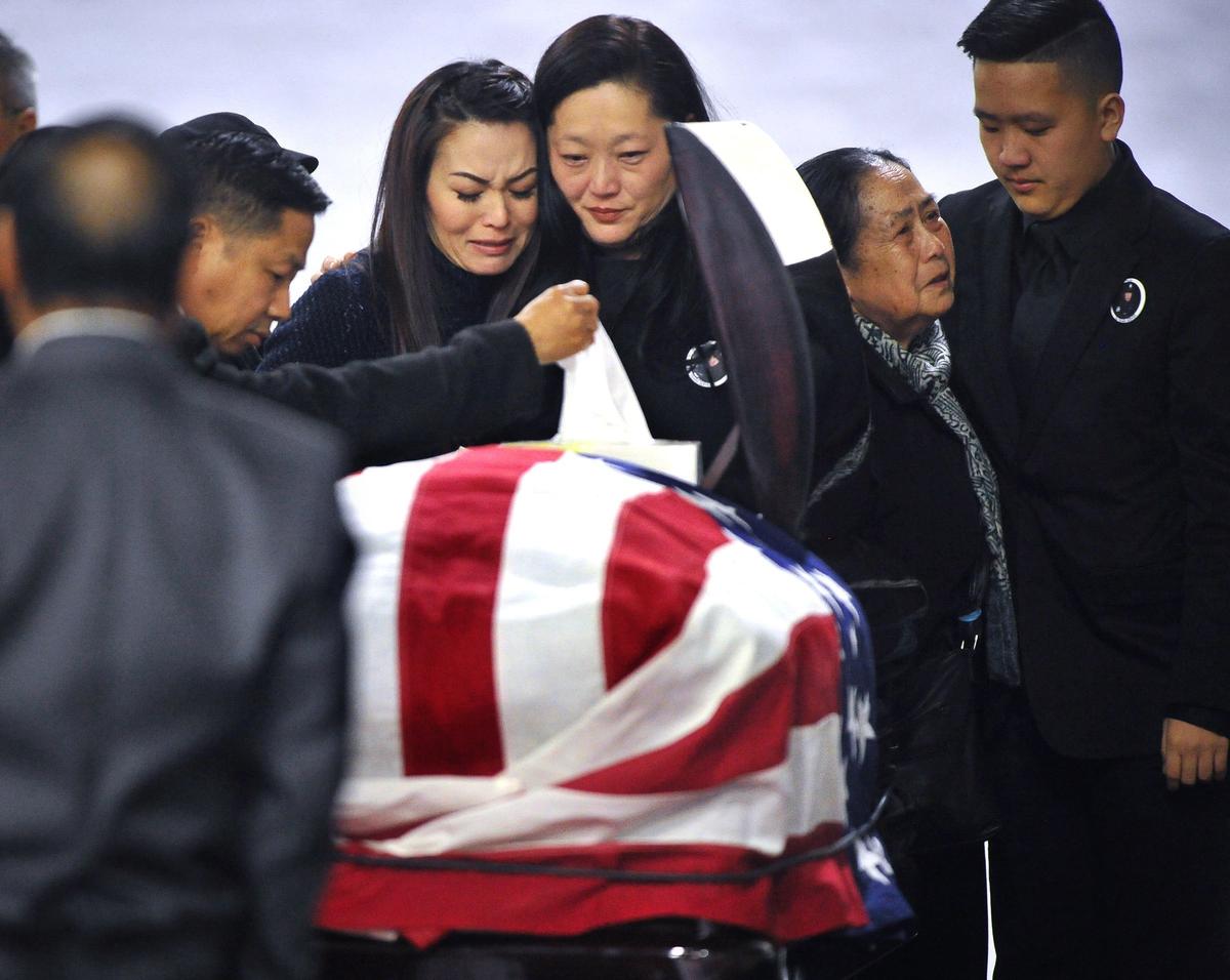 Mourners including family members gather around Ker Vang, center right, at the casket of her husband, Fresno police officer Phia Vang, on the first day of his three-day funeral services at the Fresno Convention Center Exhibit Hall on Friday Feb. 22, 2019.