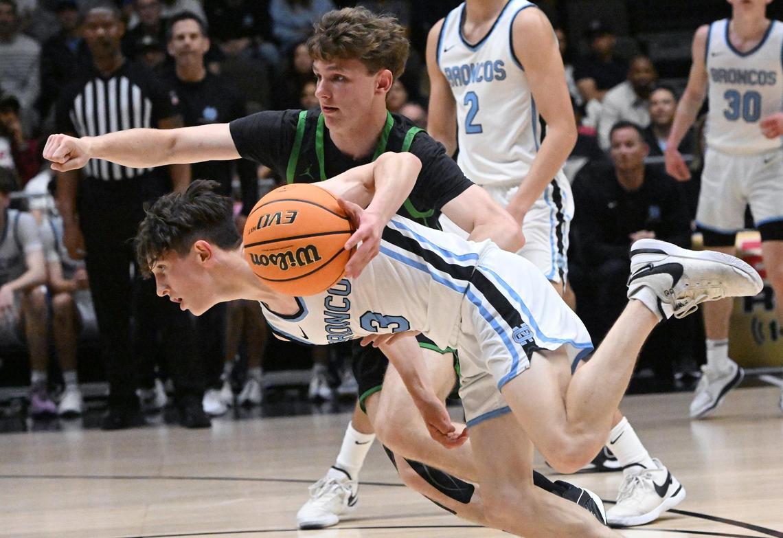 Clovis North’s McKae Amundsen, foreground drives past St. Joseph’s Diesel Lowe, background, in the Central Section Division I basketball championship Saturday, Feb. 24, 2024 at Selland Arena in Fresno.