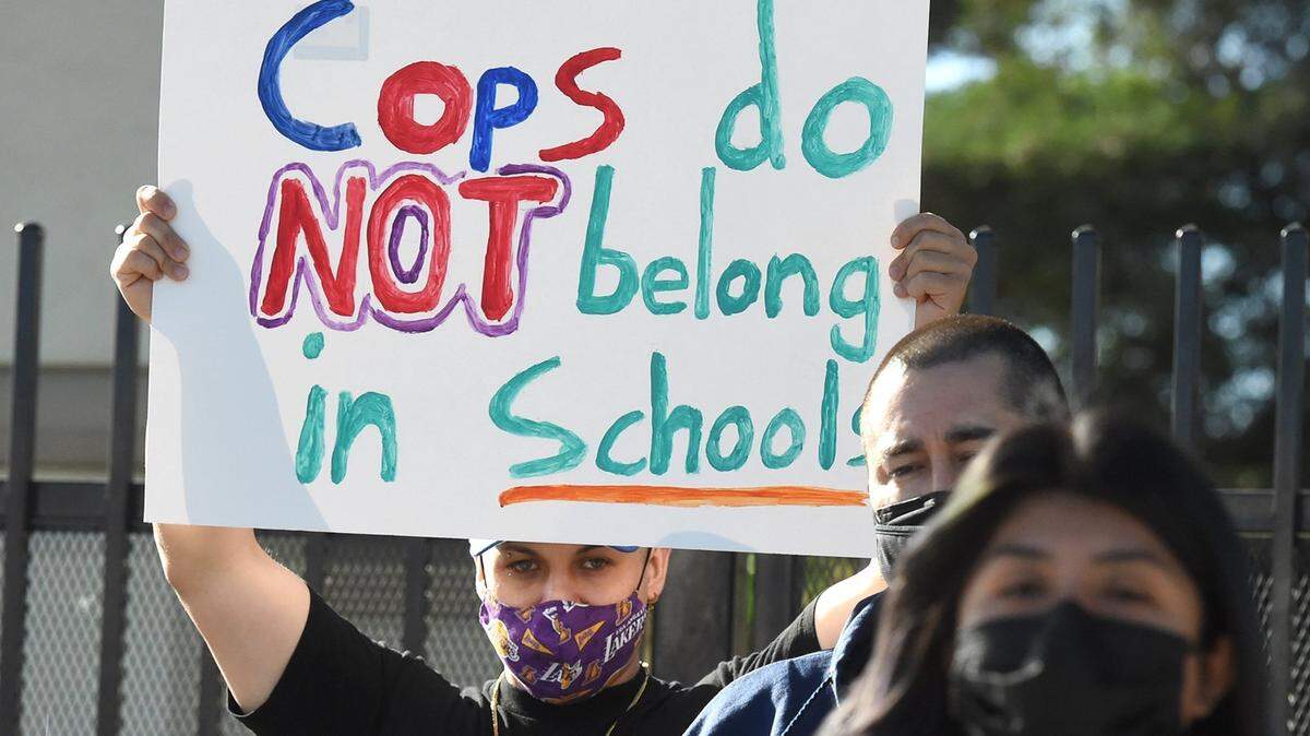 A demonstrator holds a sign as Marinarde Soto, a Fresno Unified parent, speaks during a press conference, Tuesday June 8, 2021, to urge FUSD to cut $3.2 million in campus cops funding and redirect that funding to mental-health related programs. The board ended up approving the spending.