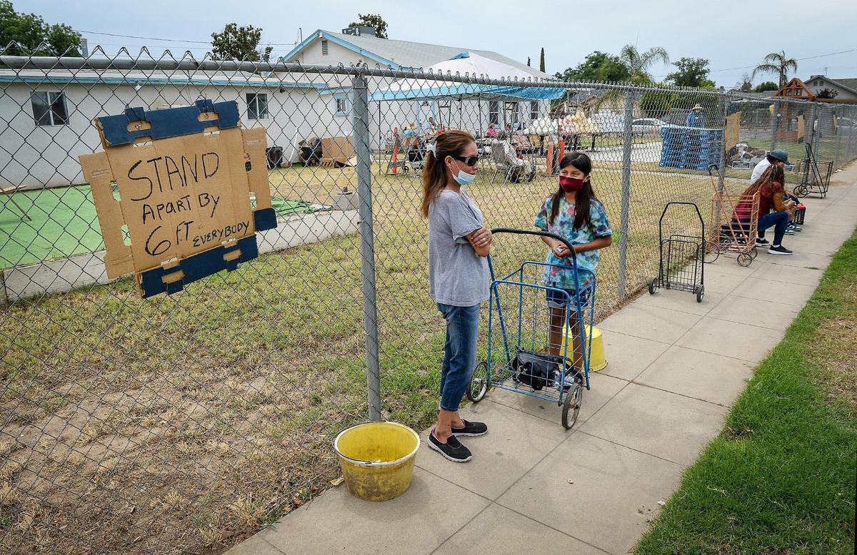 Community members in west Fresno wait for a food distribution to start at Feed My Sheep Ministries where groups and individuals are separated by six feet due to coronavirus protocols on Friday, June 5, 2020.
