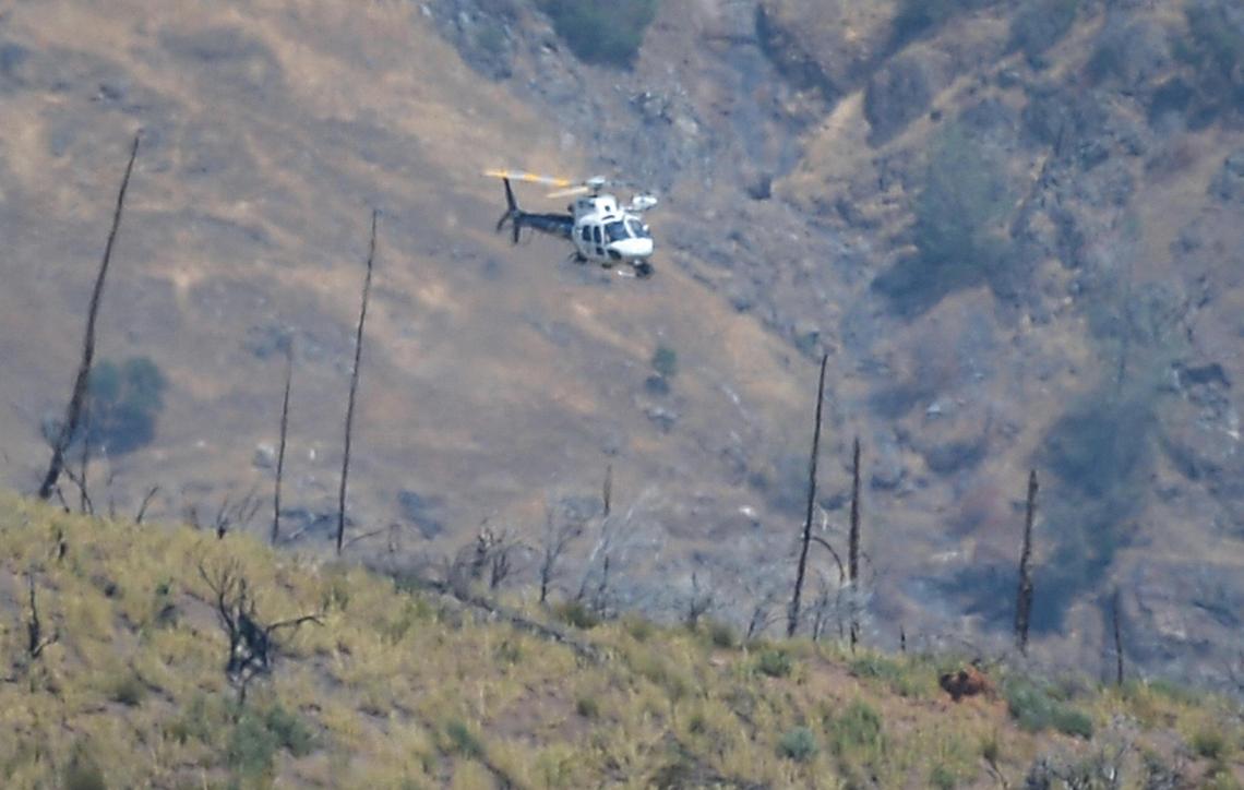 A helicopter hovers over a remote area northeast of the town of Mariposa, on Wednesday, Aug. 18, 2021. The area is reported to be where a family and their dog was found dead on Tuesday, the Mariposa County Sheriff’s Office said.
