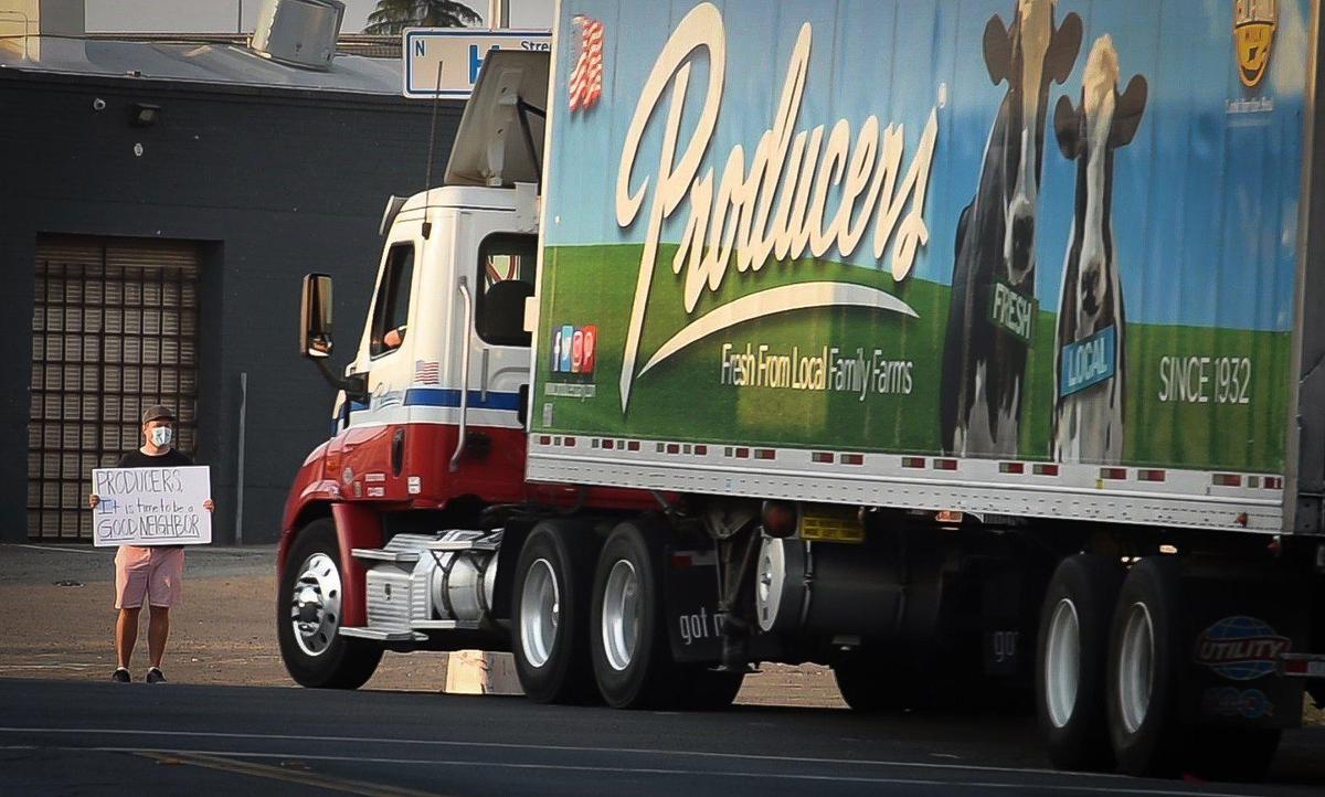 A Producers Dairy truck drives past a protestor on H Street early Thursday morning Sept. 3, 2020, who joined others in voicing opposition to a proposal by Producers Dairy Foods to close off the busy street for the industry’s truck parking.
