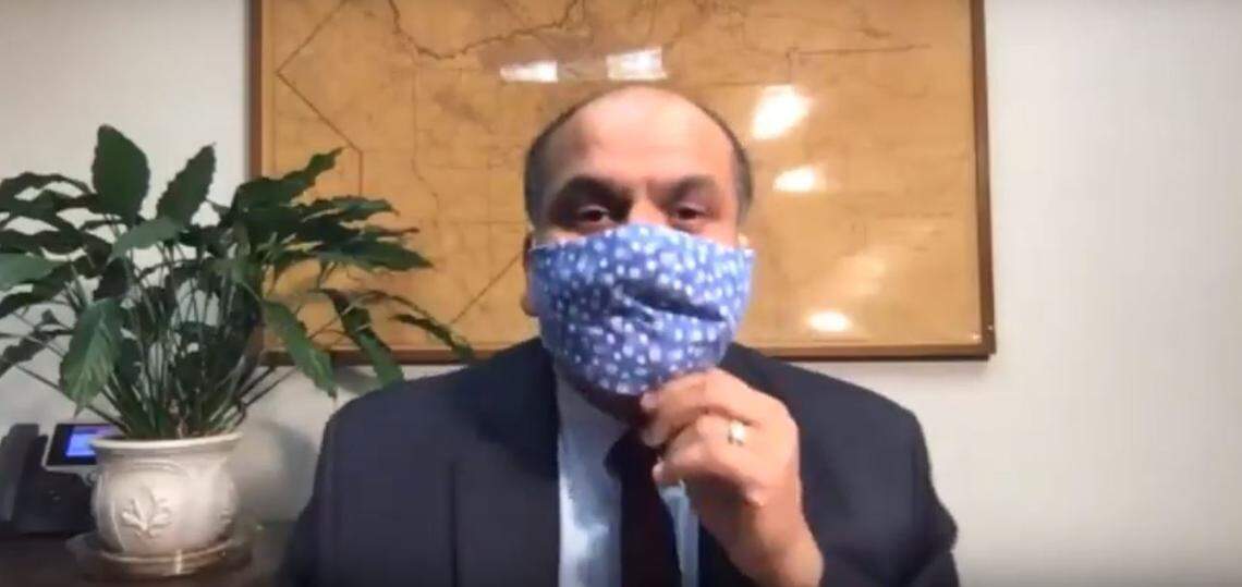 Dr. Rais Vohra, interim health officer for the Fresno County Department of Public Health, dons a fabric mask at the start of a videoconference to provide an update on cononavirus disease cases in the county on Monday, April 6, 2020.