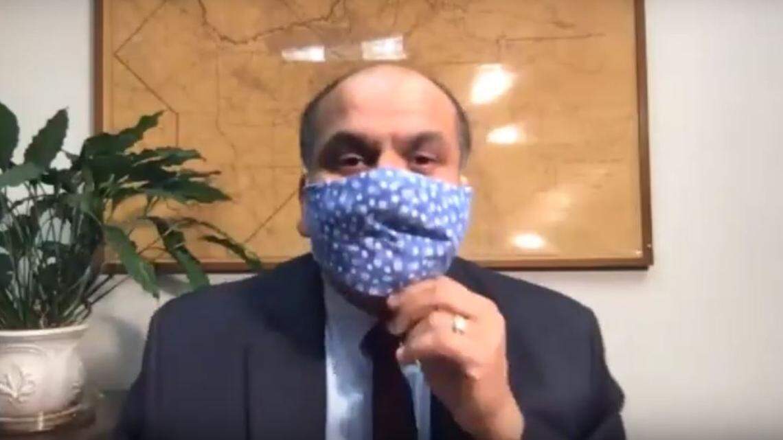 Dr. Rais Vohra, interim health officer for the Fresno County Department of Public Health, dons a fabric mask at the start of a videoconference to provide an update on cononavirus disease cases in the county on Monday, April 6, 2020.