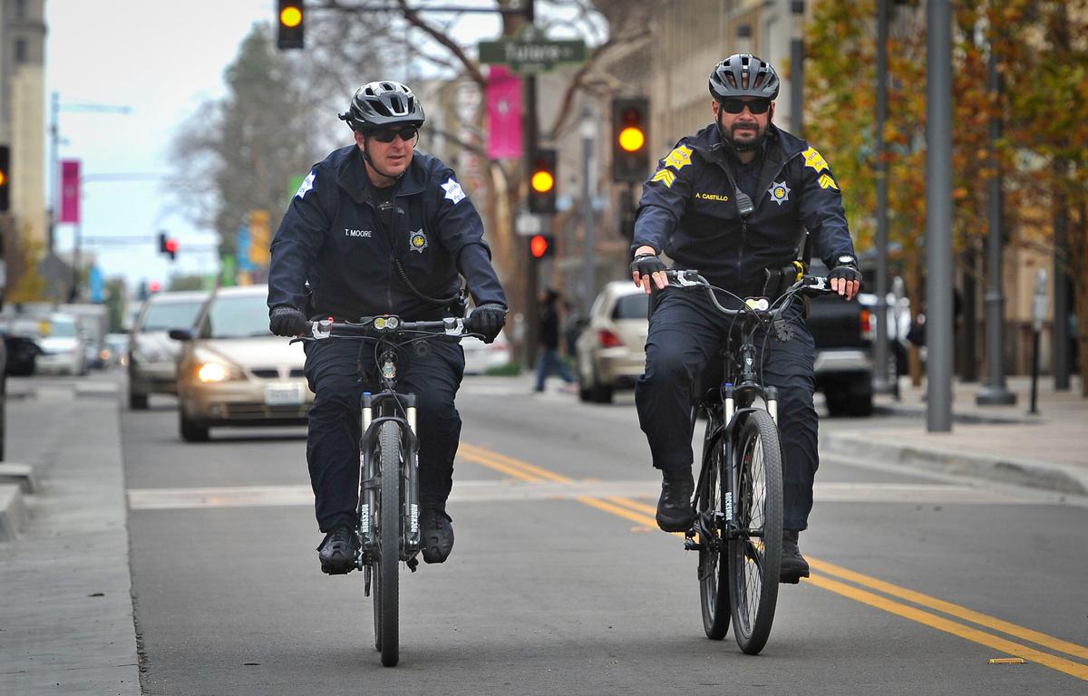 Miembros de la patrulla en bicicleta de la Unidad de Policía del Centro de Fresno, T.J. Moore, izquierda, y el sargento Alfonso Castillo, patrullan Fulton Street, en el centro de la ciudad, el 28 de febrero de 2019.