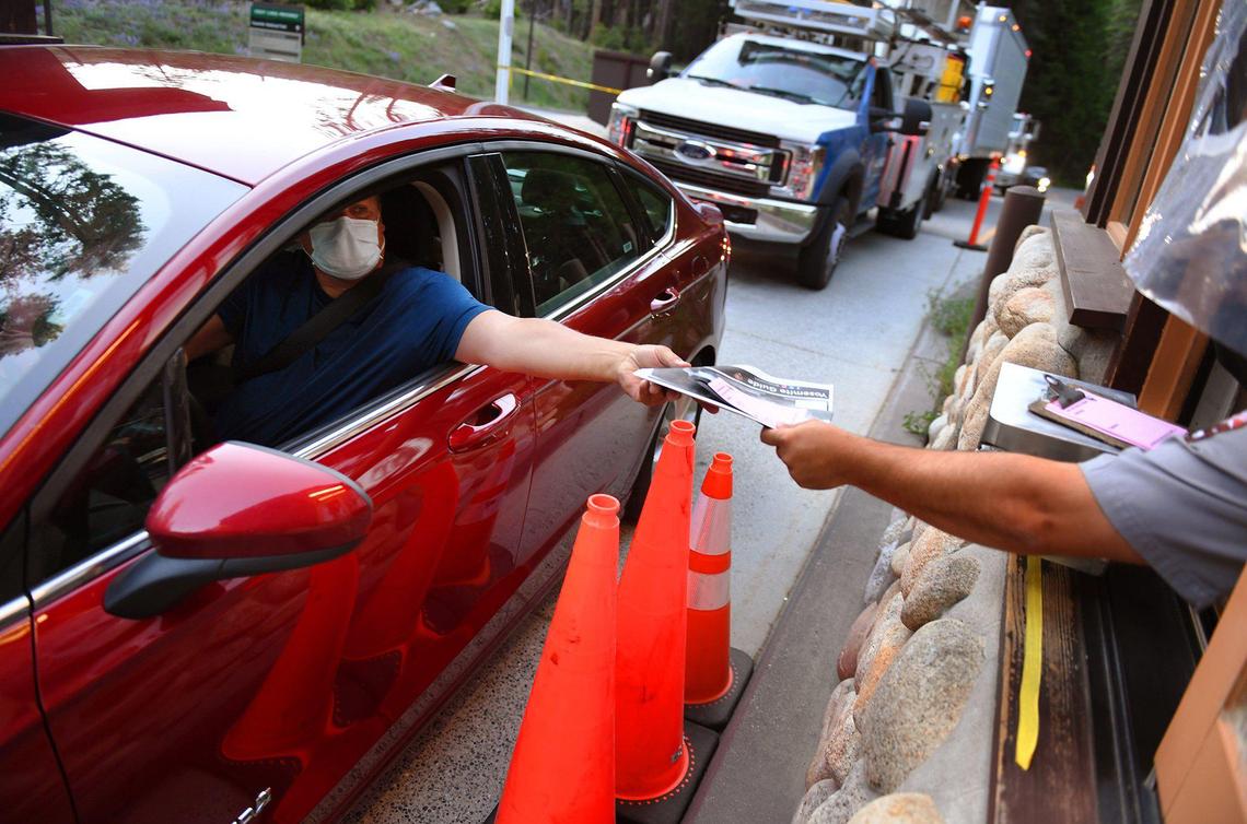James Otterman, from Virginia, left, takes park information after checking in at the south entrance as Yosemite National Park re-opens after a historic closure Thursday, June 11, 2020. Otterman said he was on his way to see the couple’s daughter in Northern California and the timing was perfect for a visit to Yosemite.