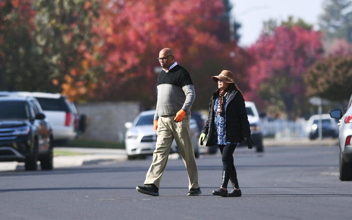 Michael Carter, left, accompanied by his wife Doreen Cometa-Carter, crosses the street as he commits Random Acts of Kindness each Monday, regularly pulling his neighbors’ trash cans from the curb and placing them against their houses. Photographed Monday, Nov. 21, 2022 in Clovis.