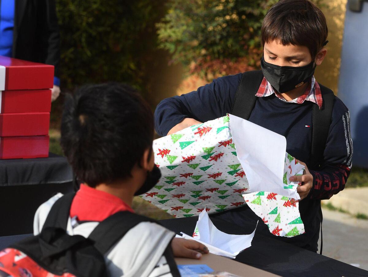 9-year-old Isaiah Martinez unwraps his new computer at the Boys & Girls Clubs of Fresno County on Tuesday Dec. 15, 2020, during a drive-through event sponsored by Comcast. Fifty children got computers in the Lift Zones program that is expected to expand internet access for the youth. Holiday boxed meals along with turkeys were provided by Central Valley Food Bank.