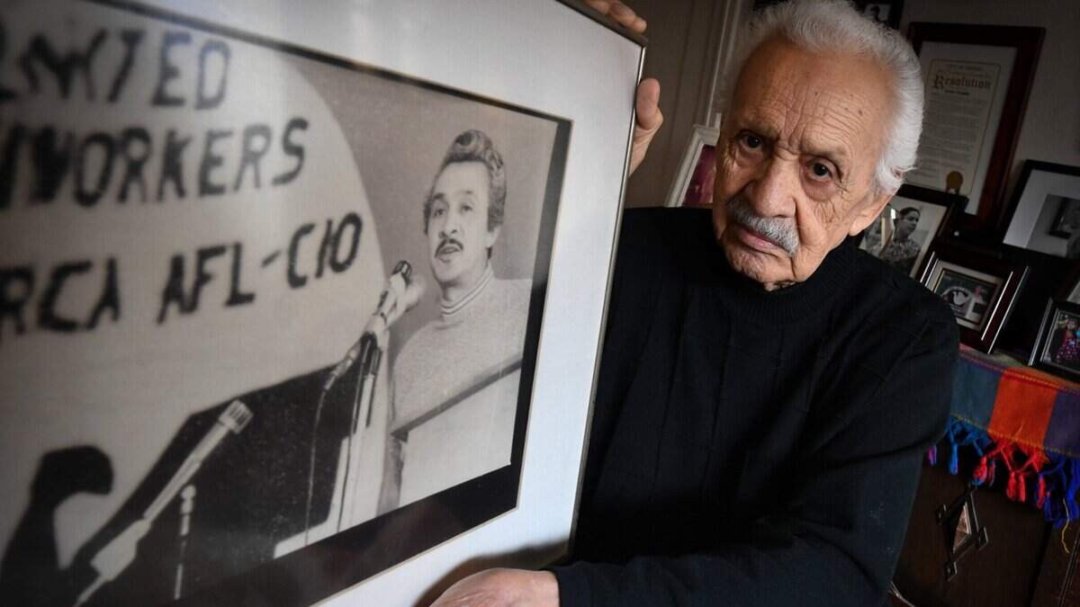 Gilbert Padilla, in his Fresno home in November 2021, holds a photograph of him speaking at an farm labor rally in Oxnard, circa 1976. Padilla, Cesar Chavez and Dolores Huerta are recognized as the co-founders of the farm worker movement that led to the creation and establishment of the United Farm Workers union.