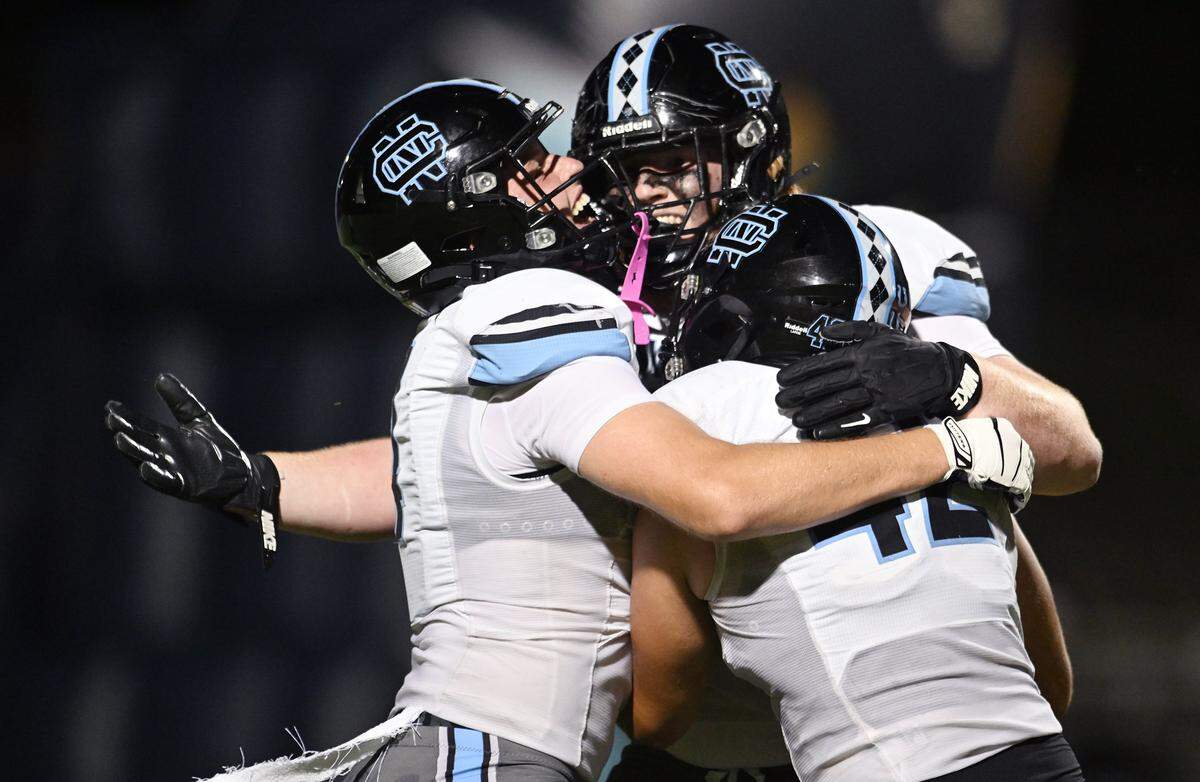 Clovis North's Ramzee Hamm, left, and Micah Solis, right, celebrate Jackson Reilly's recovered fumble, center, on a punt by Redwood for a touchdown Friday, Aug. 29, 2025 in Visalia. Clovis North held off Redwood for a 38-34 win.