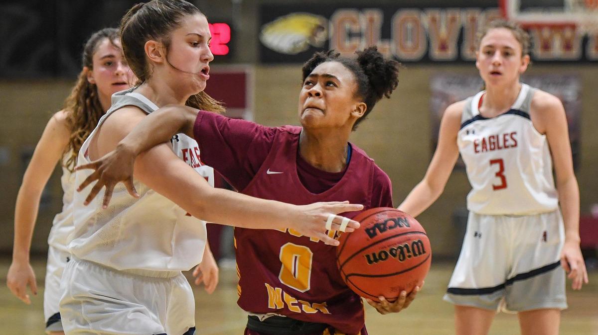 Clovis West’s Athena Tomlinson, center, tries to drive around Heritage’s Jillian Hurley, left, on her way to the hoop during their game in the annual Nike Central Valley Showdown girls basketball tournament at Clovis West High School on Friday, Dec. 3, 2021.