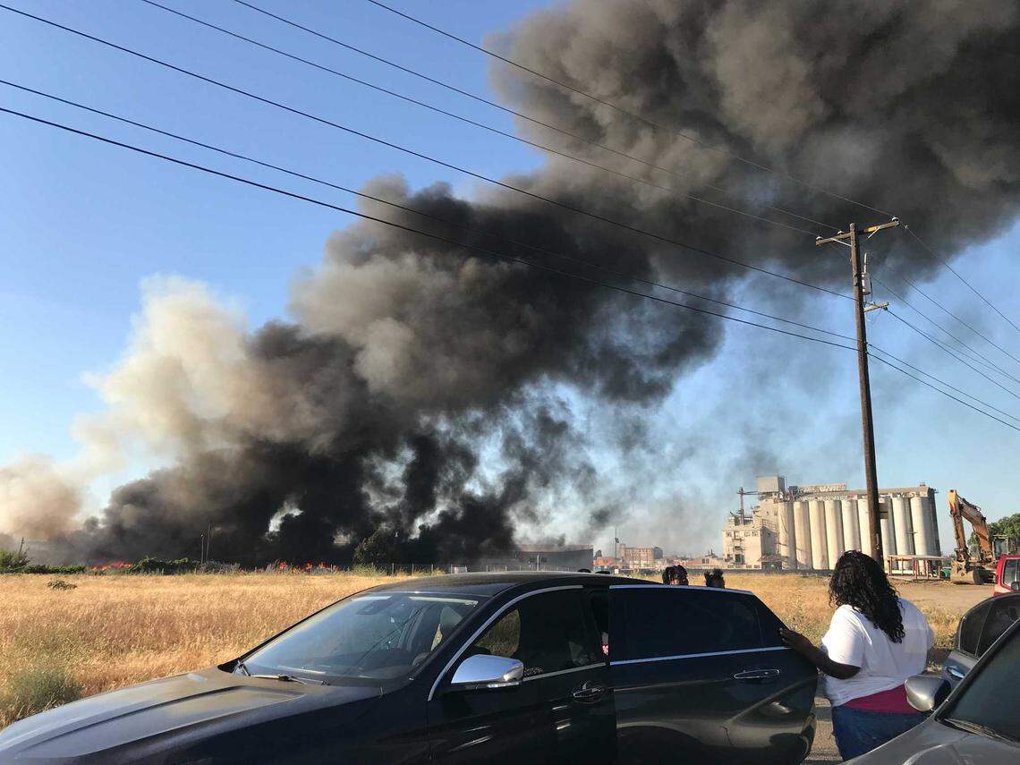 Motorists watch as a fire burns at a warehouse Saturday, June 26, 2021 in Fresno, California.