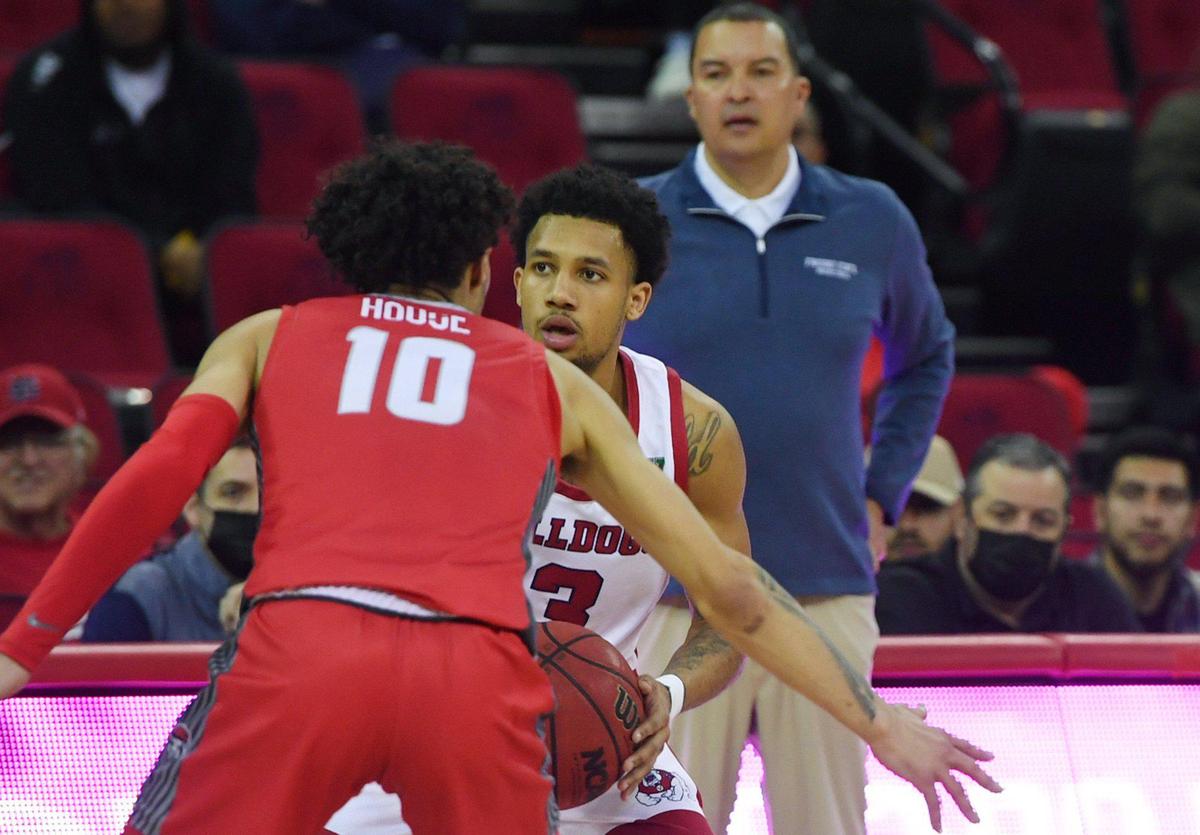 Fresno State’s Isaiah Hill, center, watched by head coach Justin Hutson, background, with New Mexico’s Jaelen House in the foreground Monday, Feb. 28, 2022 in Fresno.