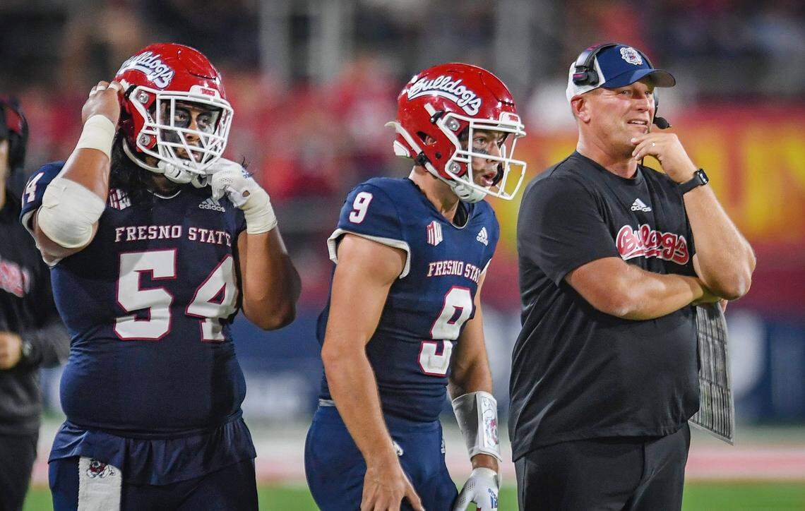 Fresno State head coach Kalen DeBoer, right, keeps watch over the action as Bulldog quarterback Jake Haener, center, and lineman Bula Schmidt get ready to take the field during their game against UNLV at Bulldog Stadium on Friday, Sept. 24, 2021.