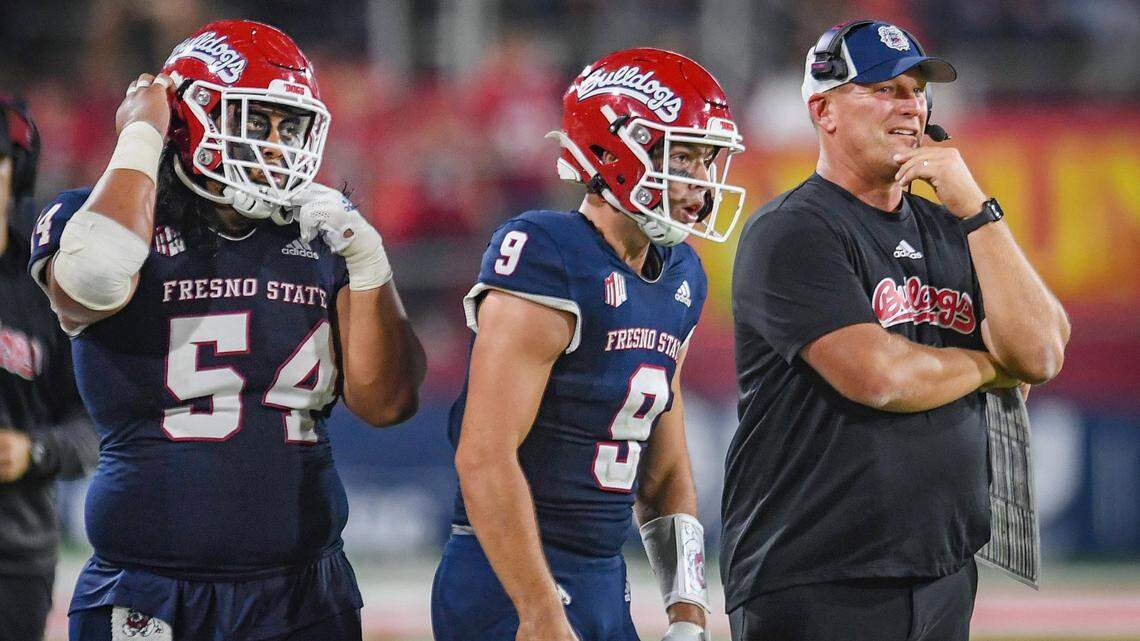 Fresno State head coach Kalen DeBoer, right, keeps watch over the action as Bulldog quarterback Jake Haener, center, and lineman Bula Schmidt get ready to take the field during their game against UNLV at Bulldog Stadium on Friday, Sept. 24, 2021.