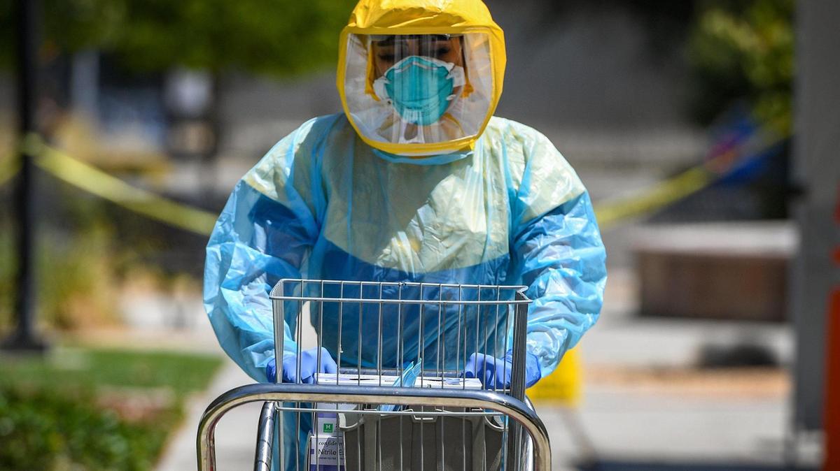 Certified medical assistant Selina Gomez from Clinica Sierra Vista in Fresno, walks a cart with COVID-19 testing equipment out to the drive-up testing area at the facility on Saturday, Aug. 8, 2020. Free COVID-19 testing was made available with an appointment.