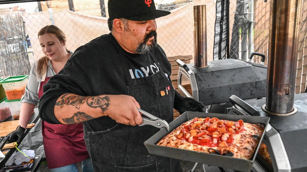 Sergio Porras puts a pan pizza in the oven while working at his Panned Pizza pop-up business with his wife Stefani on the patio at Spokeasy in Fresno in this file photo from 2023.