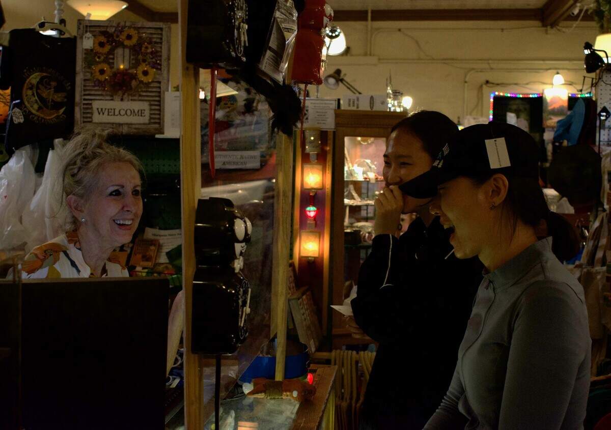Celee Evans, left, a vendor at the Mariposa Marketplace, rings up Hyewon Koo, center, and Gyeongeun Park, right, Monday night. The pair of customers, both 27-year-olds from South Korea, said they visited Yosemite National Park on Monday, and will be going to Las Vegas too.