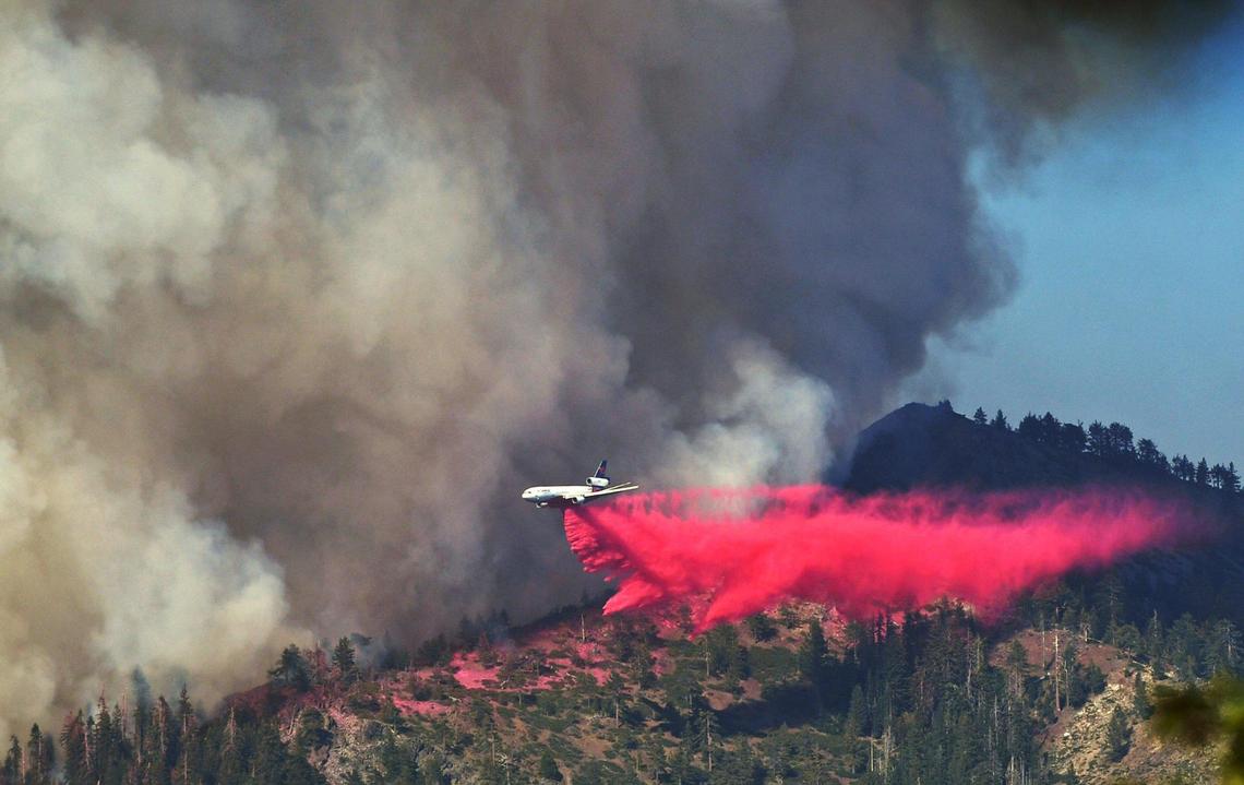 A plane drops fire retardant as the Washburn Fire as it burns near the Mariposa Grove of giant sequoias and the south entrance of Yosemite National Park Monday.