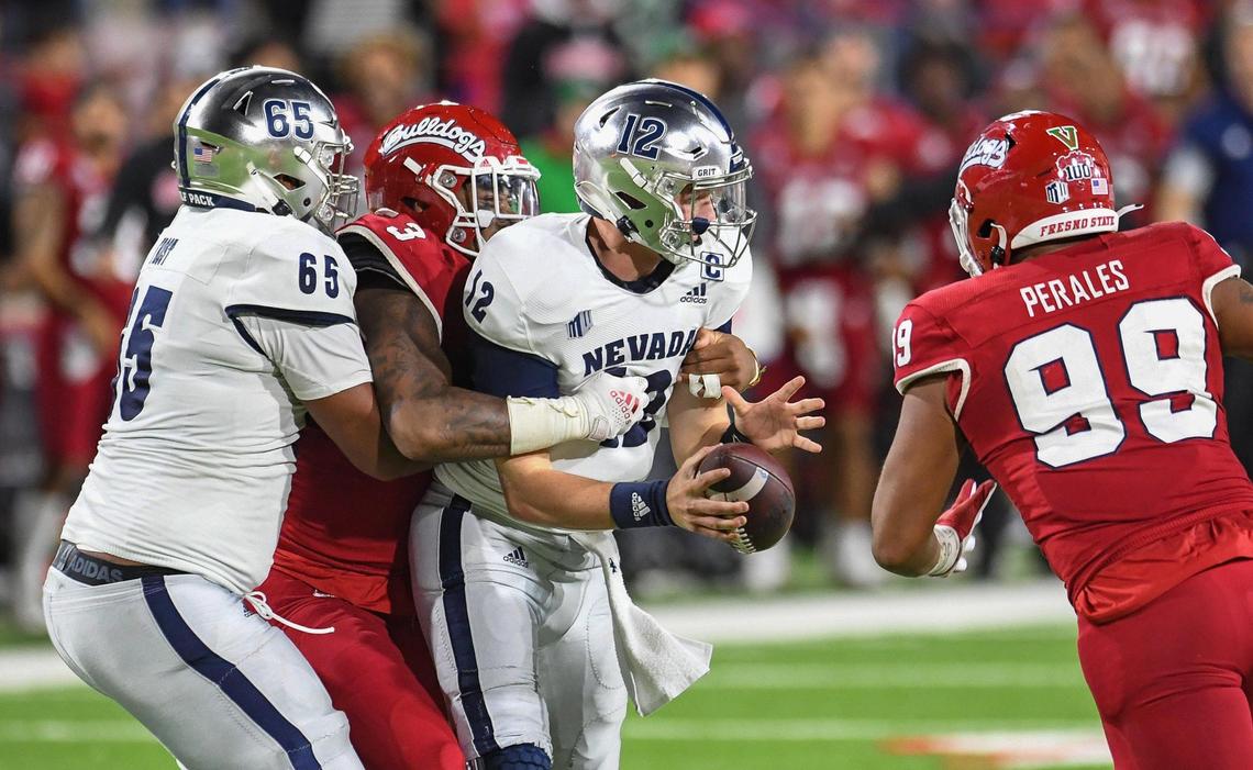 Fresno State’s Arron Mosby, second from left, and David Perales, right, combine to sack Nevada quarterback Carson Strong during their game at Bulldog Stadium on Saturday, Oct. 23, 2021.