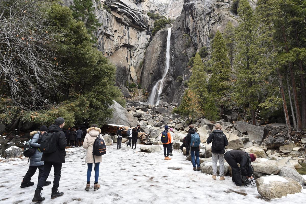 Tourists walk on ice as they approach the Lower Yosemite Falls, Tuesday, Dec. 4, 2018.