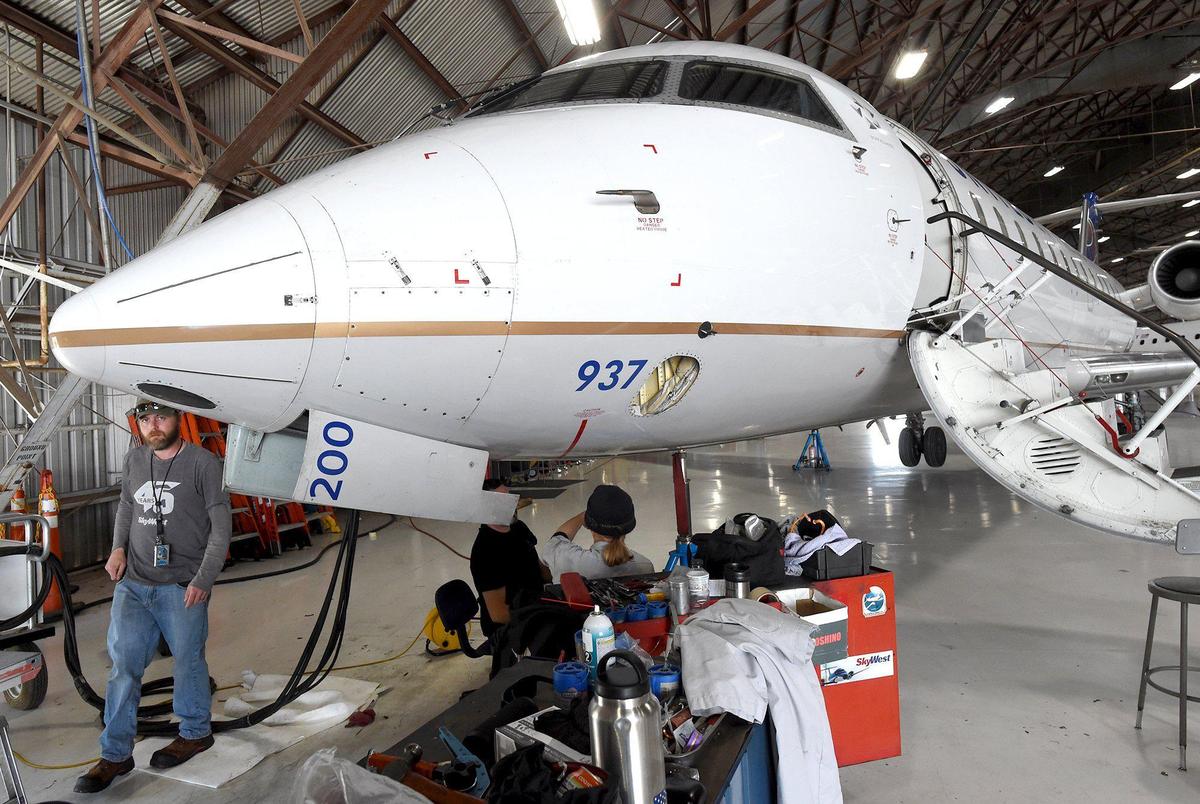 SkyWest Airlines mechanics perform maintenance on a CRJ200 regional jet in the airline’s hanger at Fresno Yosemite International Airport on March 9, 2022. The aircraft is similar to one the airline is negotiating to provide to San Joaquin Valley College’s aviation maintenance technology program for students to learn on, said Eli Mayes, SkyWest’s director of maintenance. The airline and the college are partnering on an apprenticeship program for SJVC graduates.