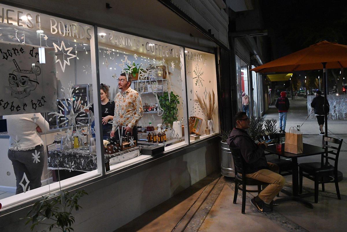 Co-owners Briena Poulter and Ian Landis, center, take a customer’s order at their pop up for Bone Dry Sober Bar during Art Hop Thursday, Dec. 2, 2021 in Fresno.