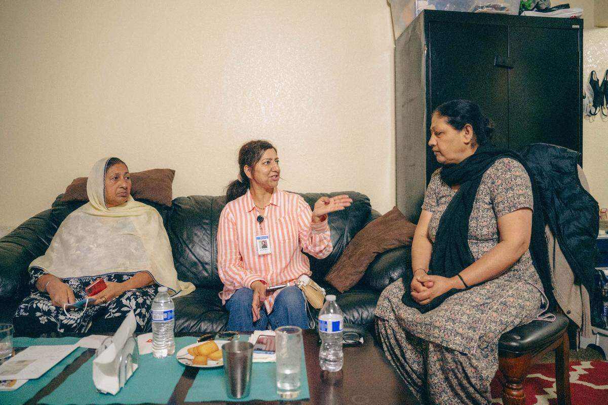 Community Health Worker Harjit Kaur, center, speaks with meat packing worker Manjit Kaur as her friend, Kulwant Kaur, looks on. Manjit Kaur is one of many Punjabi residents in Fresno who work at area meatpacking plants. Manjit Kaur expressed thanks for help she received getting an appointment with a Punjabi-speaking dentist after she became bedridden with tooth pain and had to miss work.