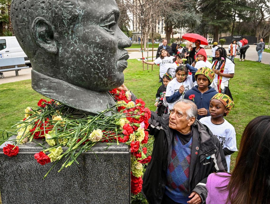 Dr. Sudarshan Kapoor, center, helps students place flowers on the MLK memorial bust during the annual Martin Luther King garlanding event at Fresno County Courthouse Park in Fresno on Friday, Jan. 13, 2023.The 39th annual events were kicked off with the garlanding ceremony at the MLK memorial bust to honor and remember slain civil rights leader Rev. Dr. Martin Luther King Jr.