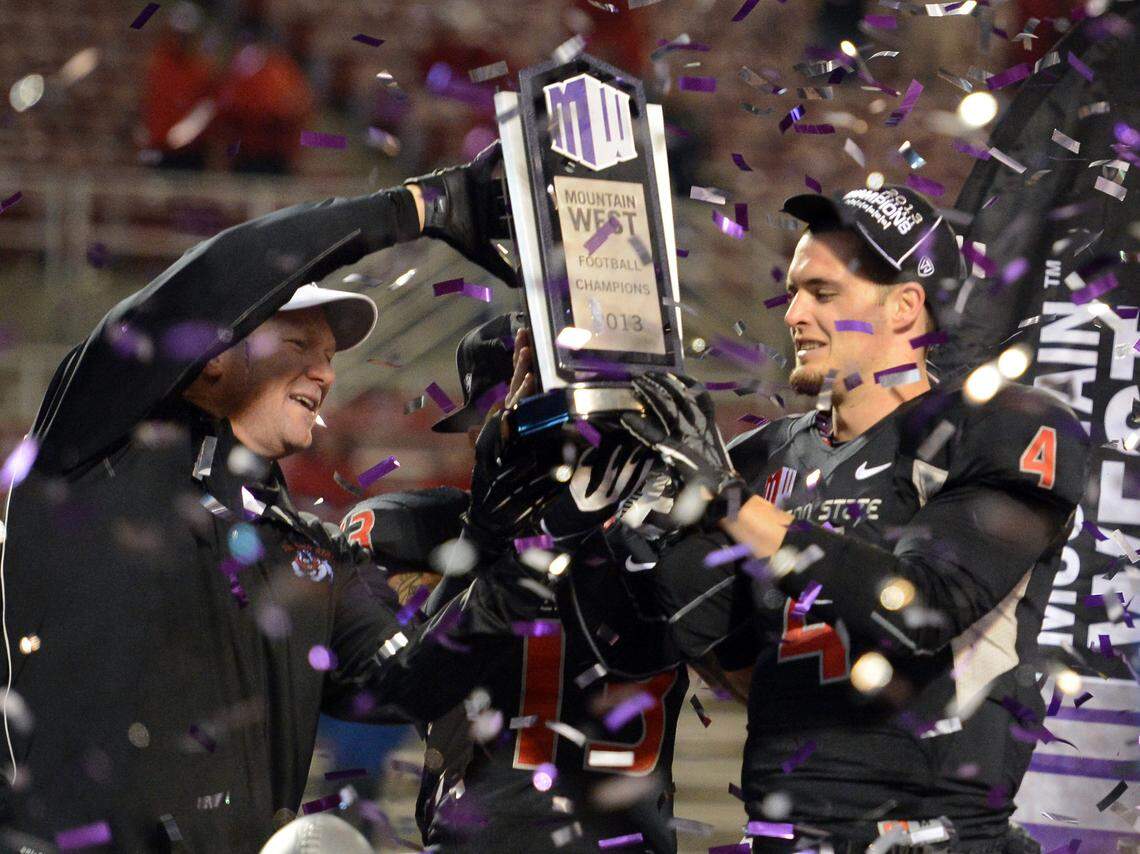 Fresno State coach Tim DeRuyter, left, and quarterback Derek Carr hold up the Mountain West conference championship trophy after the Bulldogs defeated Utah State in the conference championship game at Bulldog Stadium Saturday, December 7, 2013.