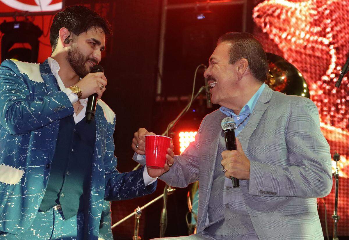El vocalista Ricardo Yocupicio Ulloa de Banda El Recodo bromea con Julio Preciado durante el último concierto del año en el parque Chukchansi en Frenso el 29 de octubre, 2022.