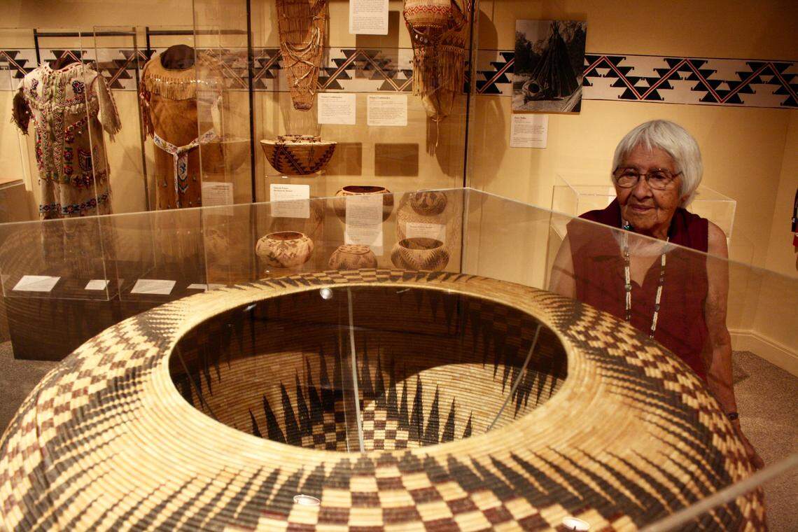 Helen Coats looks at a large basket made by her grandmother, Lucy Telles, on display in the Indian Cultural Museum in Yosemite Valley, summer 2014. In the background are an array of smaller traditional baskets, cradleboards and clothing also made by Telles.