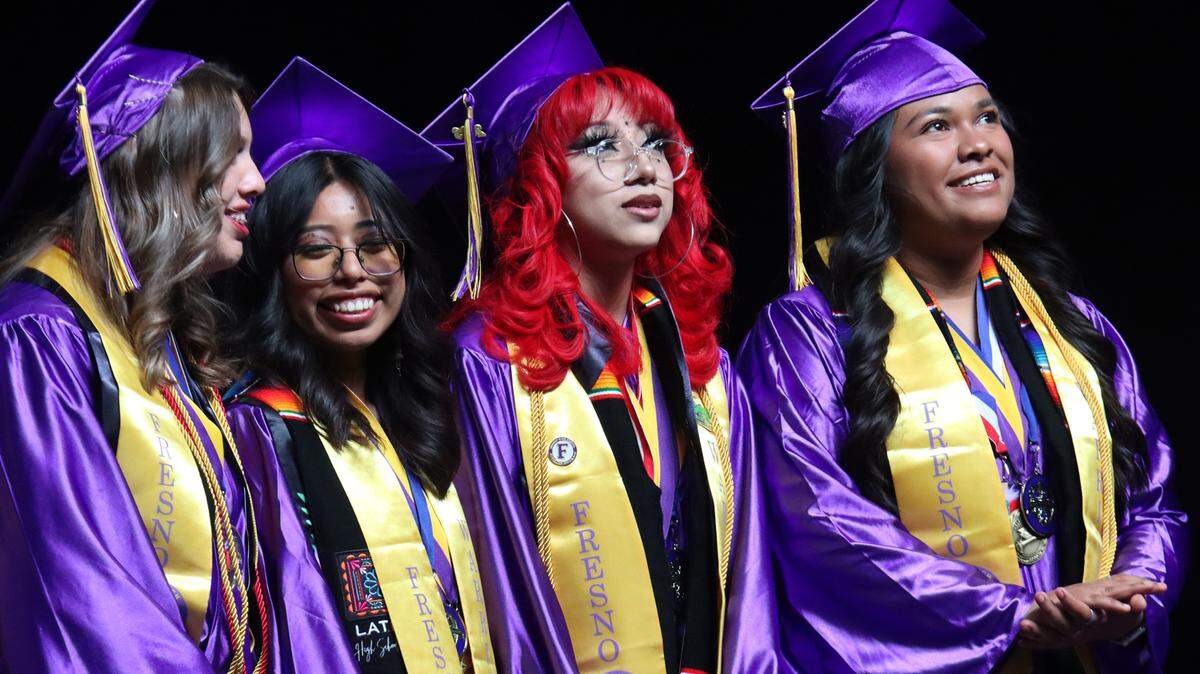 Giselle Brenda Mendoza Rendón (with red hair) looks at the video along with fellow valedictorians during the Fresno High graduation ceremony held at the Save Mart Center on June 5, 2023.