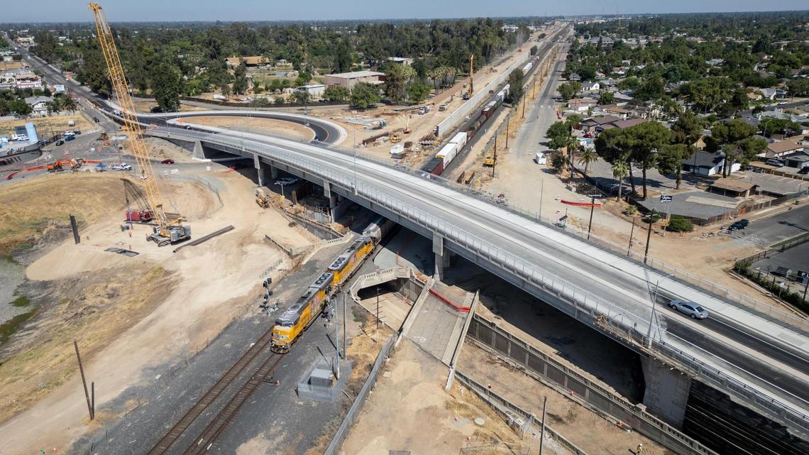 A train passes below the newly constructed Belmont Avenue overpass bridge, or grade separation, near Roeding Park in Fresno on Tuesday, June 24, 2025. The four-lane bridge is now open and will take traffic and pedestrians over the Union Pacific Railroad and high-speed rail tracks. The bridge itself spans more than 611 feet long and 62 feet wide.