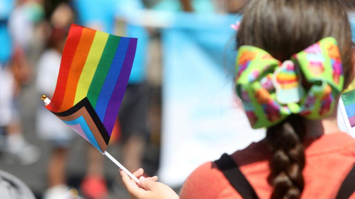 A girl waves a pride flag while watching the Fresno Rainbow Pride Parade in the Tower District on June 3, 2023.