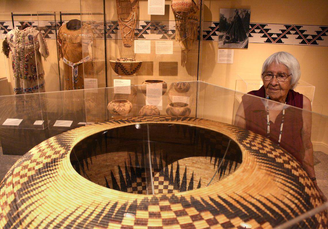 In this 2014 photo, Helen Coats, who is Miwuk and Paiute, looks at a large basket made by her grandmother Lucy Telles on display in the Indian Cultural Museum in Yosemite Valley. In the background are an array of smaller traditional baskets, cradleboards and clothes also made by Telles.