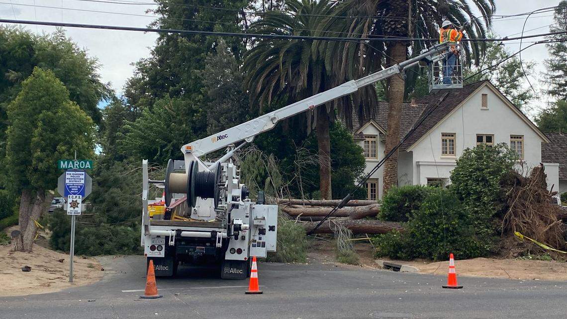 A PG&E crew works on a power line after a tree fell at Maroa and Holland avenues in Fresno, California, on Wednesday, July 22, 2022.