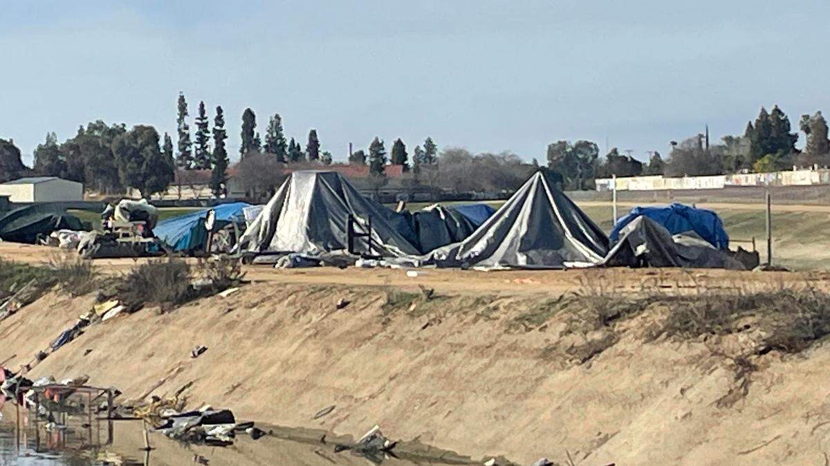 Tarps and tents were springing up along a Fresno Irrigation District canal near Dakota and Palm avenues on Friday, Feb. 23 2024. The camp is near the Fig Garden neighborhood. Unhoused advocate Dez Martinez said its a reflection of the number of people on the streets in Fresno.