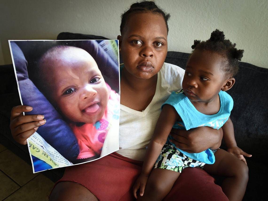 Akifa Frost, who is formerly homeless, holds a photograph of her daughter, Naszar’ie Butler, who died in July, as her 2-year-old daughter, Naszirah, looks on in their Central Fresno apartment. Frost struggled to get shelter for her family.