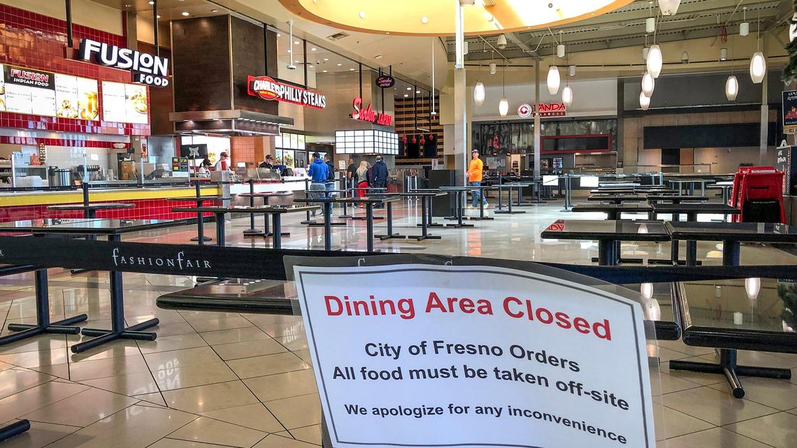 Empty tables are visible in the food court at Fashion Fair Mall in Fresno at mid day where a sign explains that all orders must be taken off-site on Wednesday, March 18, 2020. Most of the stores inside the mall have closed or reduced their hours due to concerns for the coronavirus pandemic facing the country.