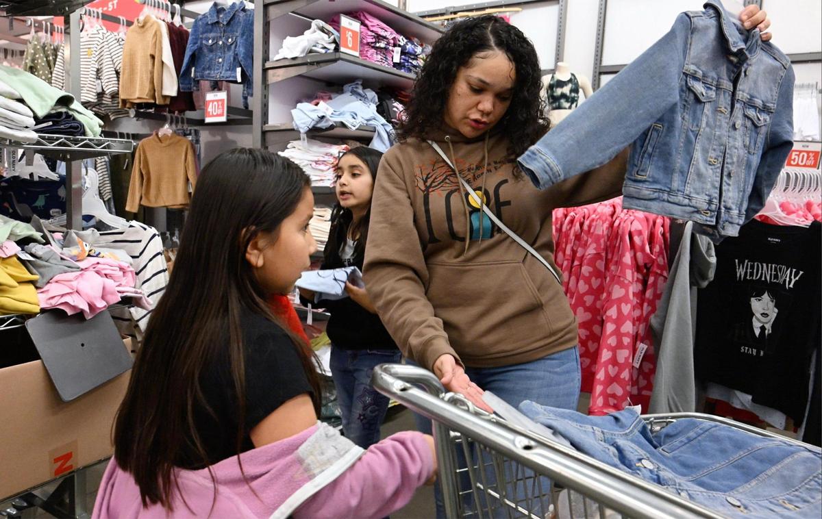 Janessa Williams, administradora de proyectos de Live Again Fresno, a la derecha, ayuda a los niños a comprobar la talla de la ropa durante una compra en Old Navy la mañana del lunes 18 de diciembre de 2023, en Fresno.