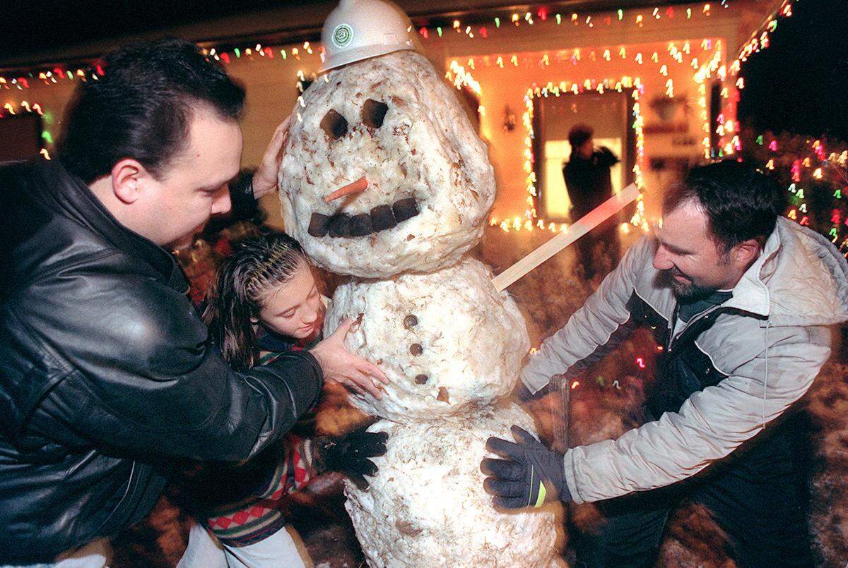 Lionel Gonzalez, left; Rebecca Webster, center, and Mark Fagundes, right, straighten a six-foot snowman they built with the snow from three front yards on Sunday, Dec. 20, 1998, in Fresno.