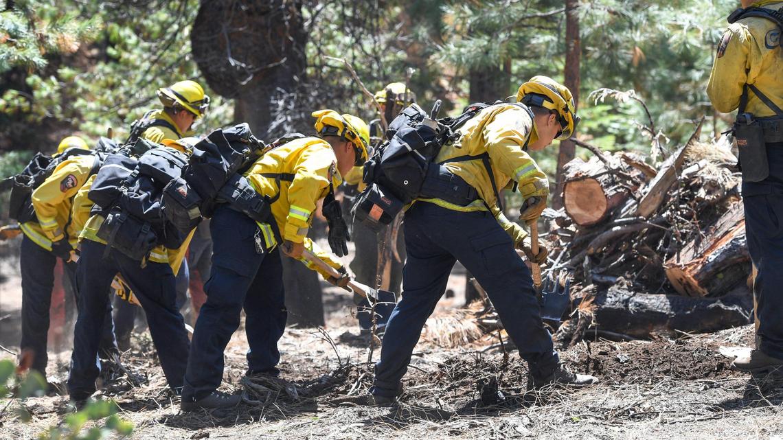 Fire crews work to clear brush and burned trees in an area burned by the Creek Fire on April 8, 2021.