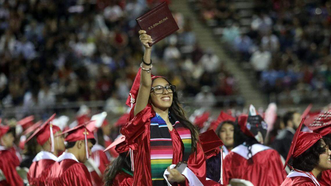 A graduate holds up her diploma during the McLane High graduation at the school stadium on June 6, 2023.