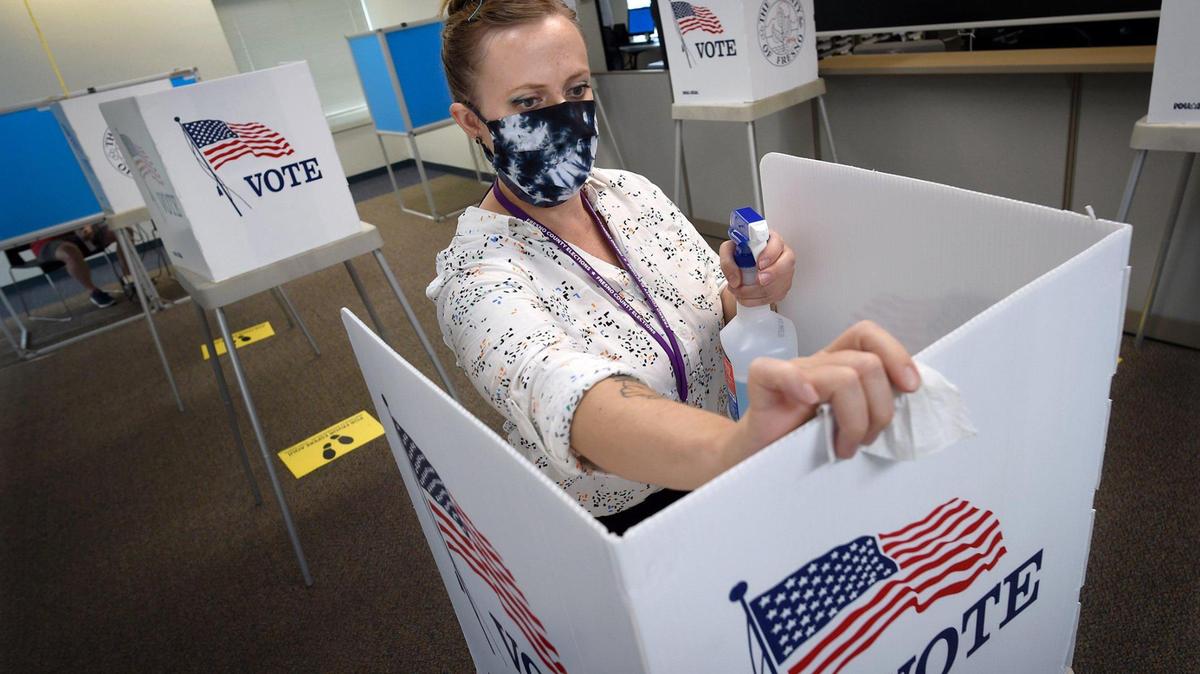 Fresno County Elections worker Kayla Lee sanitizes a voter’s booth after a person voted at the Fresno County Elections Office, Tuesday Oct. 6, 2020.