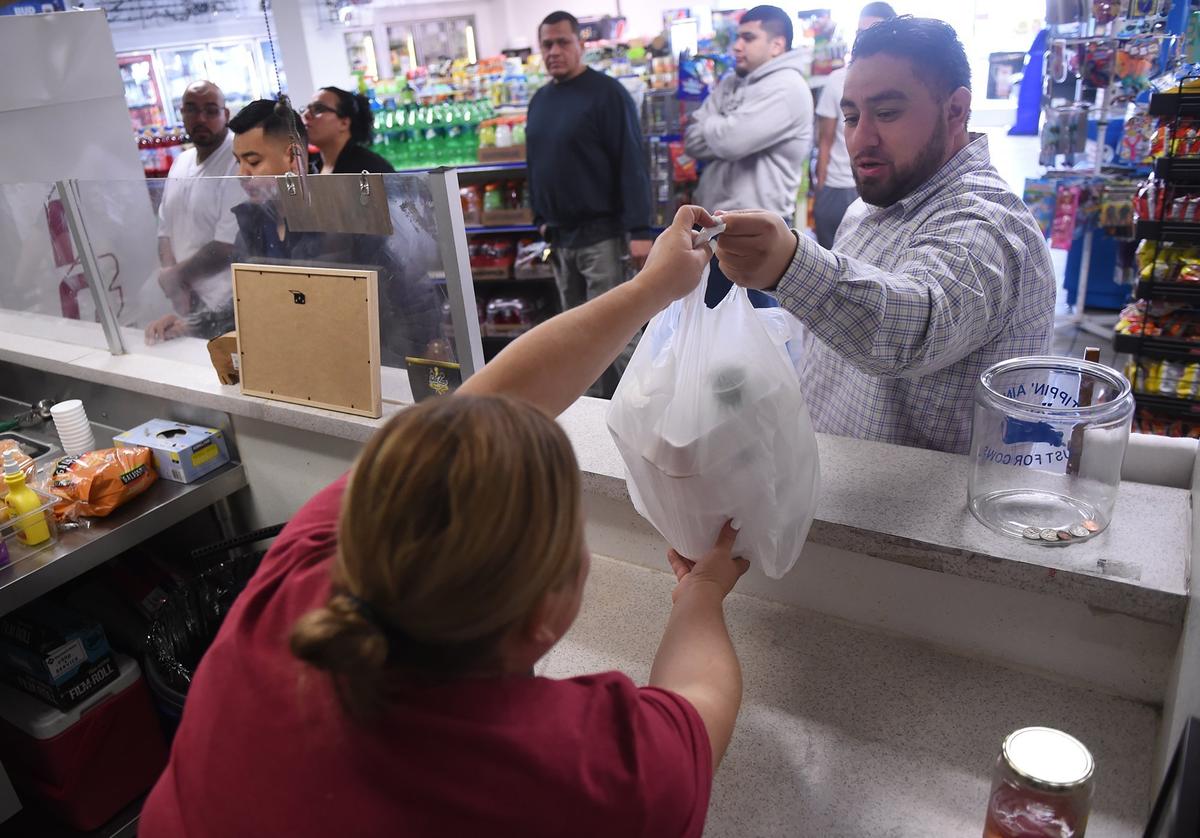 In this file photo from January 2019, Tasha Vallejo, left, hands an order to Rudy Bustamante at Mega Texas Barbeque in the Arco gas station at Fresno Street and McKinley Avenue in Fresno.