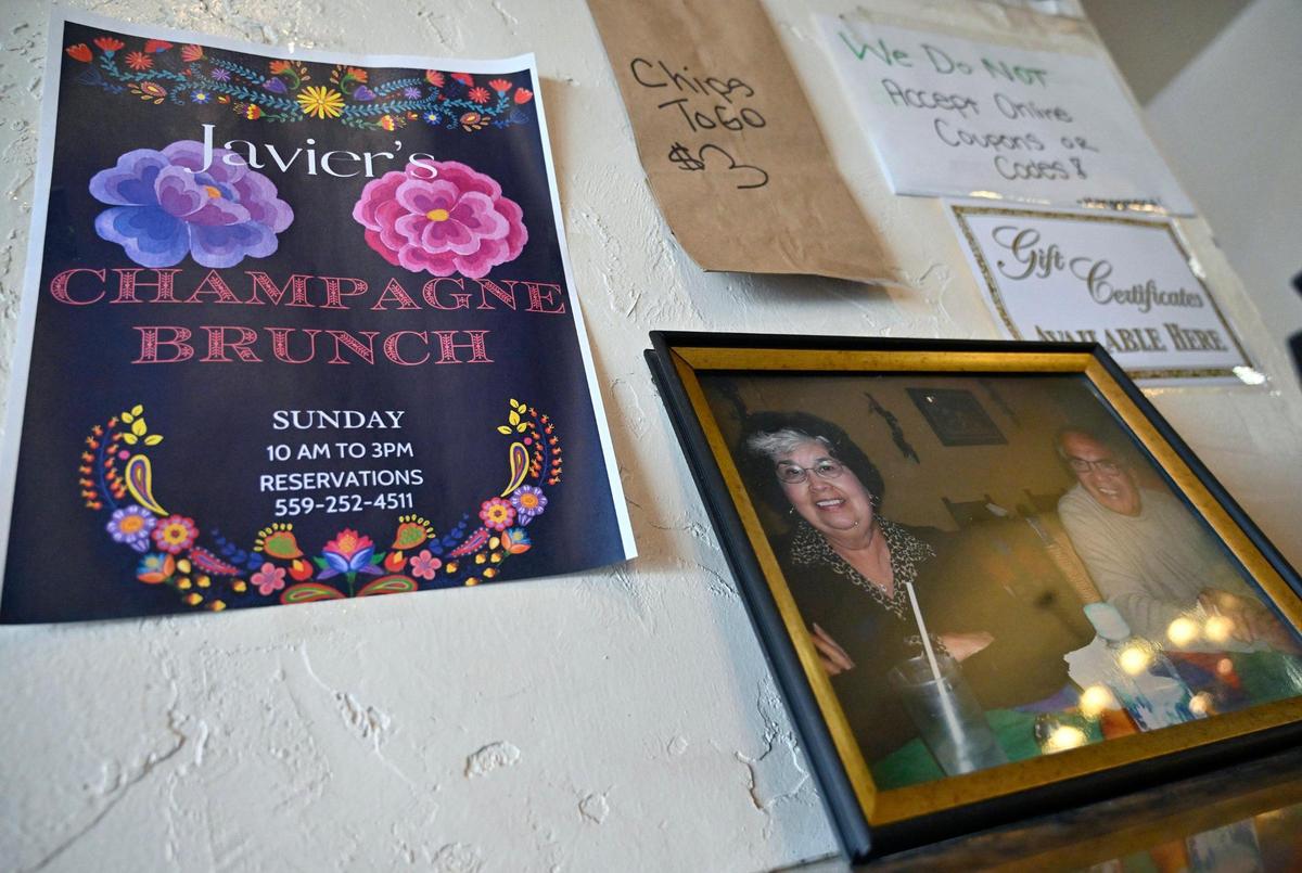 Una foto del fundador del Javier's Mexican Restaurant, Louie Durán, y su esposa, Lupe, cerca de la caja registradora junto a un anuncio del nuevo Champagne Brunch que se ofrece. Fotografiado el domingo 17 de septiembre de 2023, en Fresno.