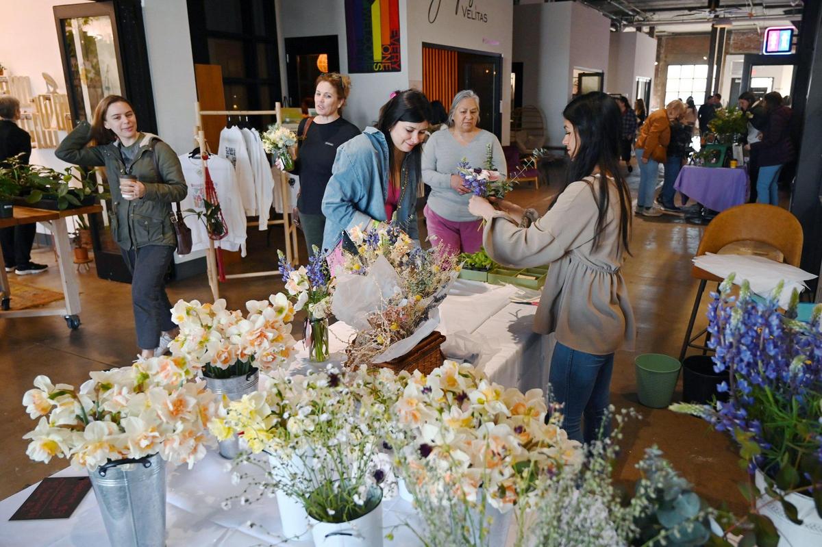 Customers shop at the first Flower Market, held inside the Sun Stereo Warehouse in downtown Fresno’s Brewery District Saturday, March 18, 2023. Owner Danielle Fischer said fresh cut specialty flowers, edible flowers and potted flowers from Central Valley growers are featured.